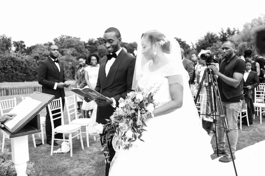 Beatiful bride, Chidinma and groom, Tolulope Olajide standing at the altar on the wedding day. Behind them are guests. Black an white picture