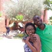 smiling young African couple Tolulope and Chidinma Olajide standing outside in embrace looking away from the camera