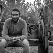 monochrome picture of a sad and pensive black ethnic millennial sitting ona a bench in the rain. Acute Grief: What early response of grieving feel like?