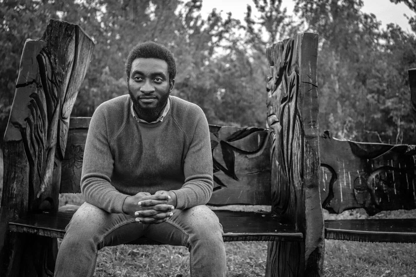 monochrome picture of a sad and pensive black ethnic millennial sitting ona a bench in the rain. Acute Grief: What early response of grieving feel like?