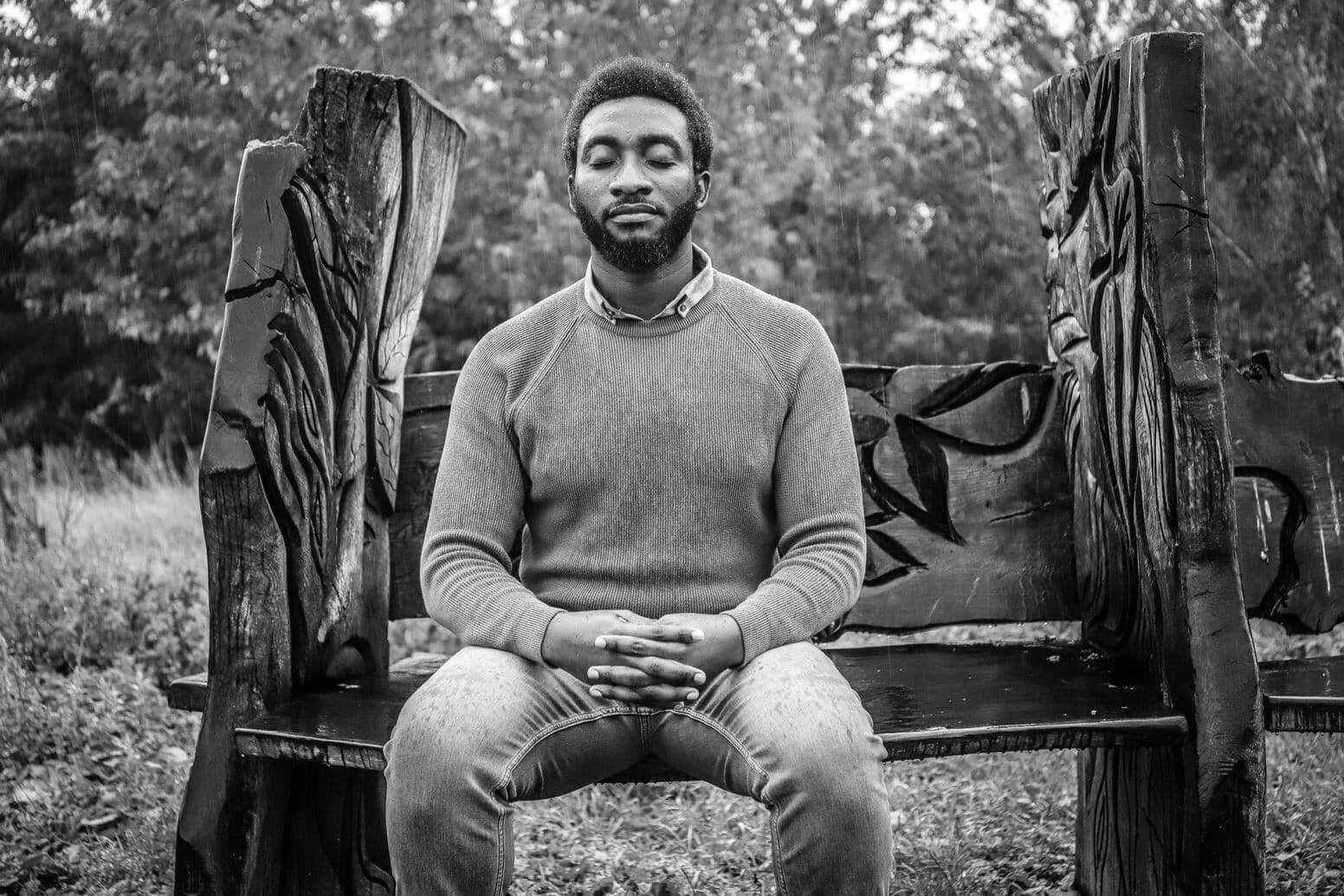 Tolulope Olajide with his eyes closed gets drenched by a heavy rain as he sits on a bench in the woodlands. Loss of Spouse; Being Widowed and Young