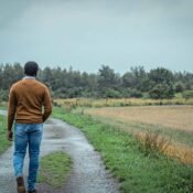 Young African male walking away from the camera. He's walking in a heavy rain on a tarred path in a meadow. What has envy got to do with grieving?