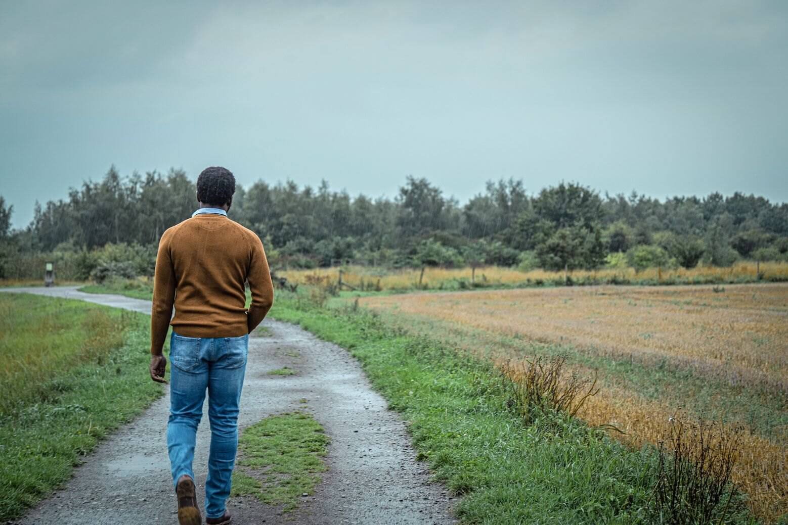 Young African male walking away from the camera. He's walking in a heavy rain on a tarred path in a meadow. What has envy got to do with grieving?